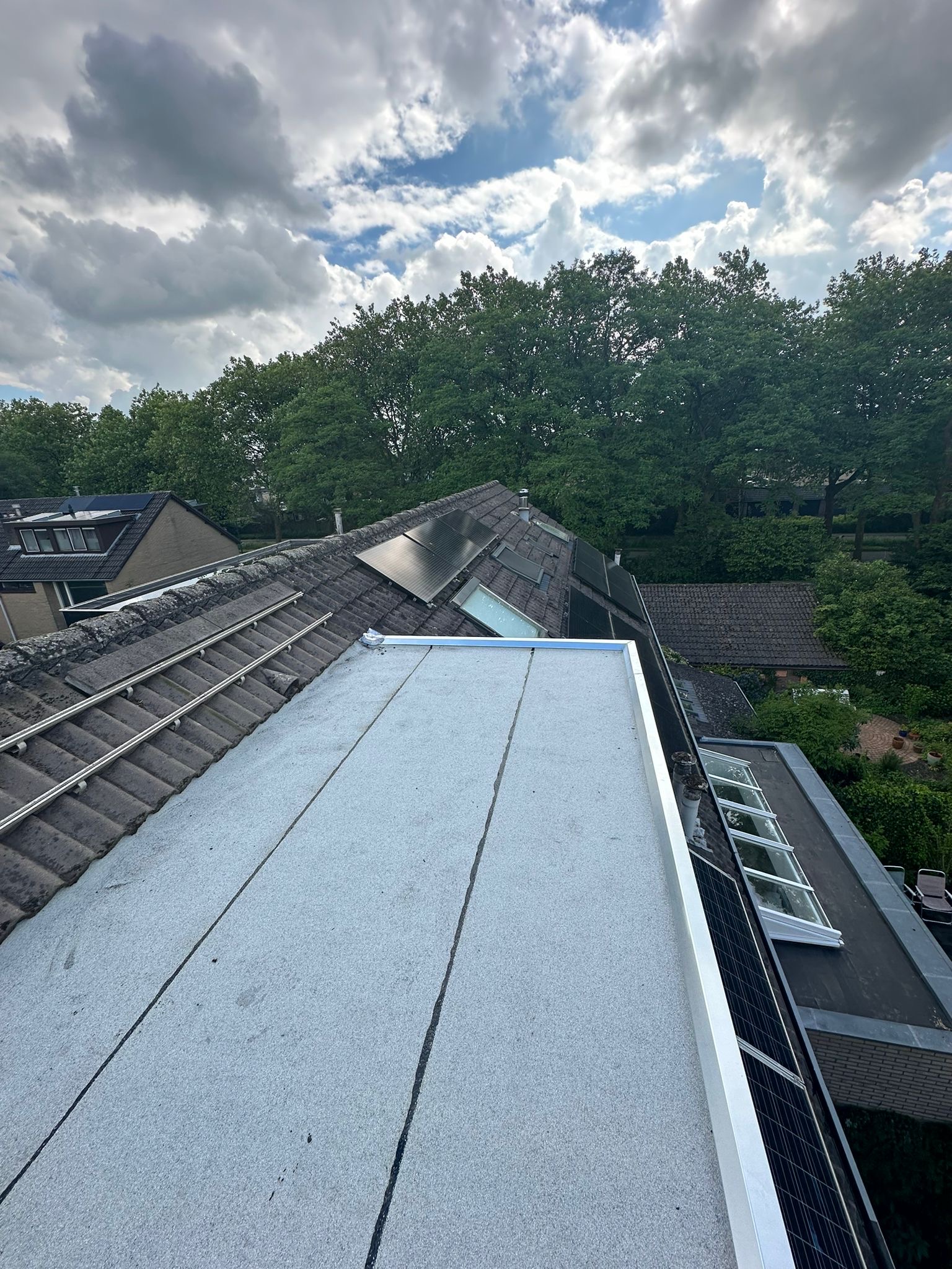 Nieuw dakkapeldak naast een pannendak met zonnepanelen