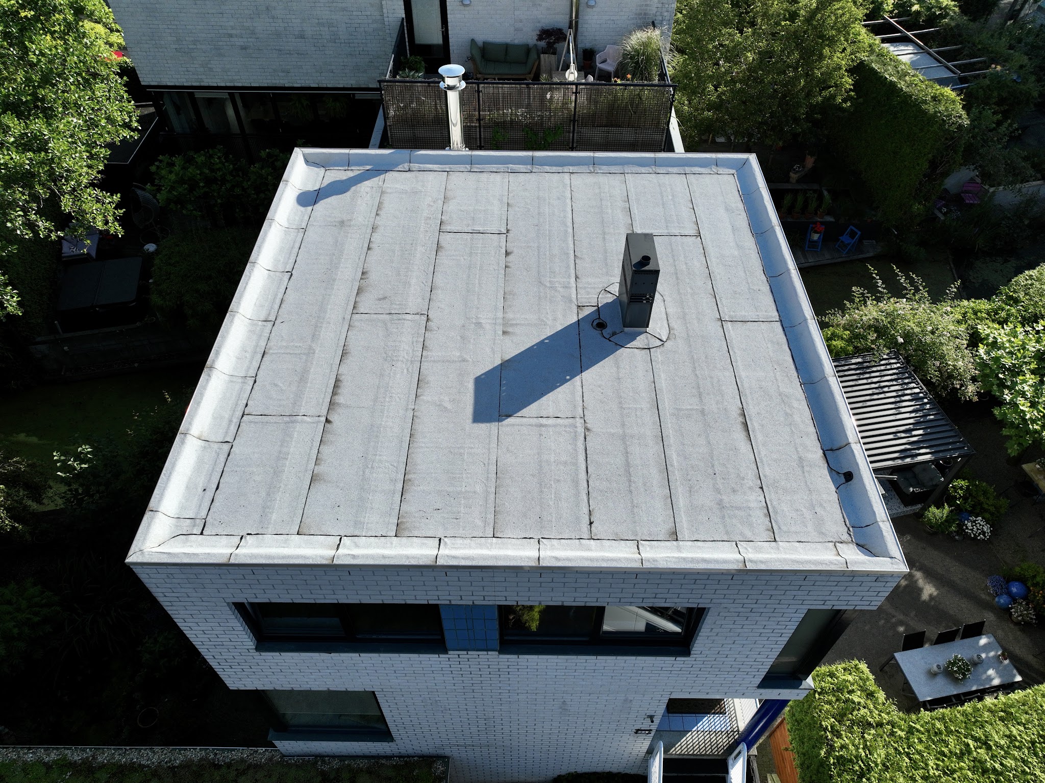 Luchtfoto van een afgewerkt plat dak op een wit gemetseld huis